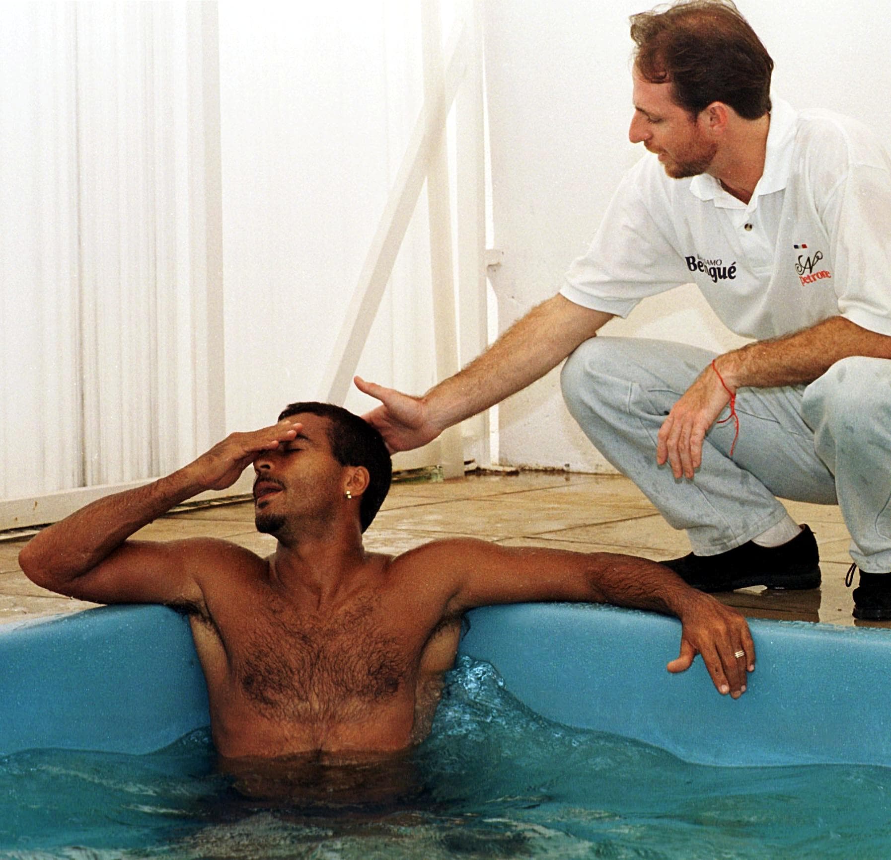 O astro do futebol brasileiro Romário (E), do clube espanhol Valencia, é consolado por seu treinador Nilton Petrone ao sentir dores no pé esquerdo, em 29 de agosto, enquanto está sentado em uma banheira de hidromassagem na clínica Petrone, no Rio de Janei