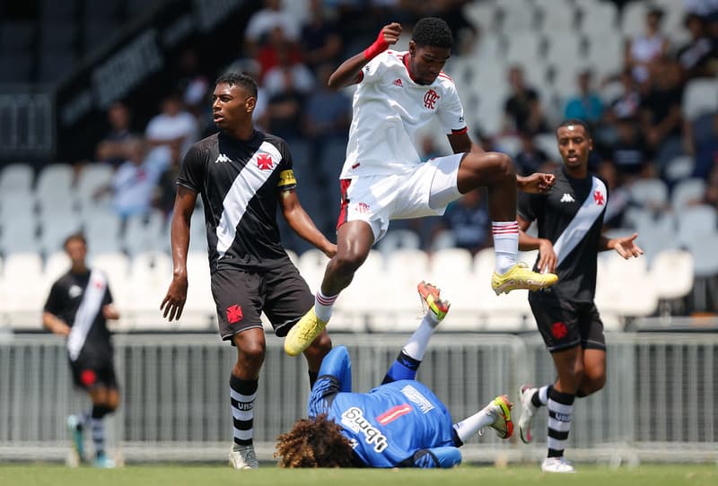 Jogador da base do Flamengo salta na disputa com jogador do Vasco na final do Campeonato Carioca 2022.