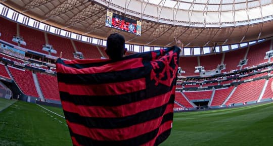 Torcedor com bandeira do Flamengo no gramado do Estádio Mané Garrincha. Flamengo faz no estádio um test drive da gestão do Maracanã