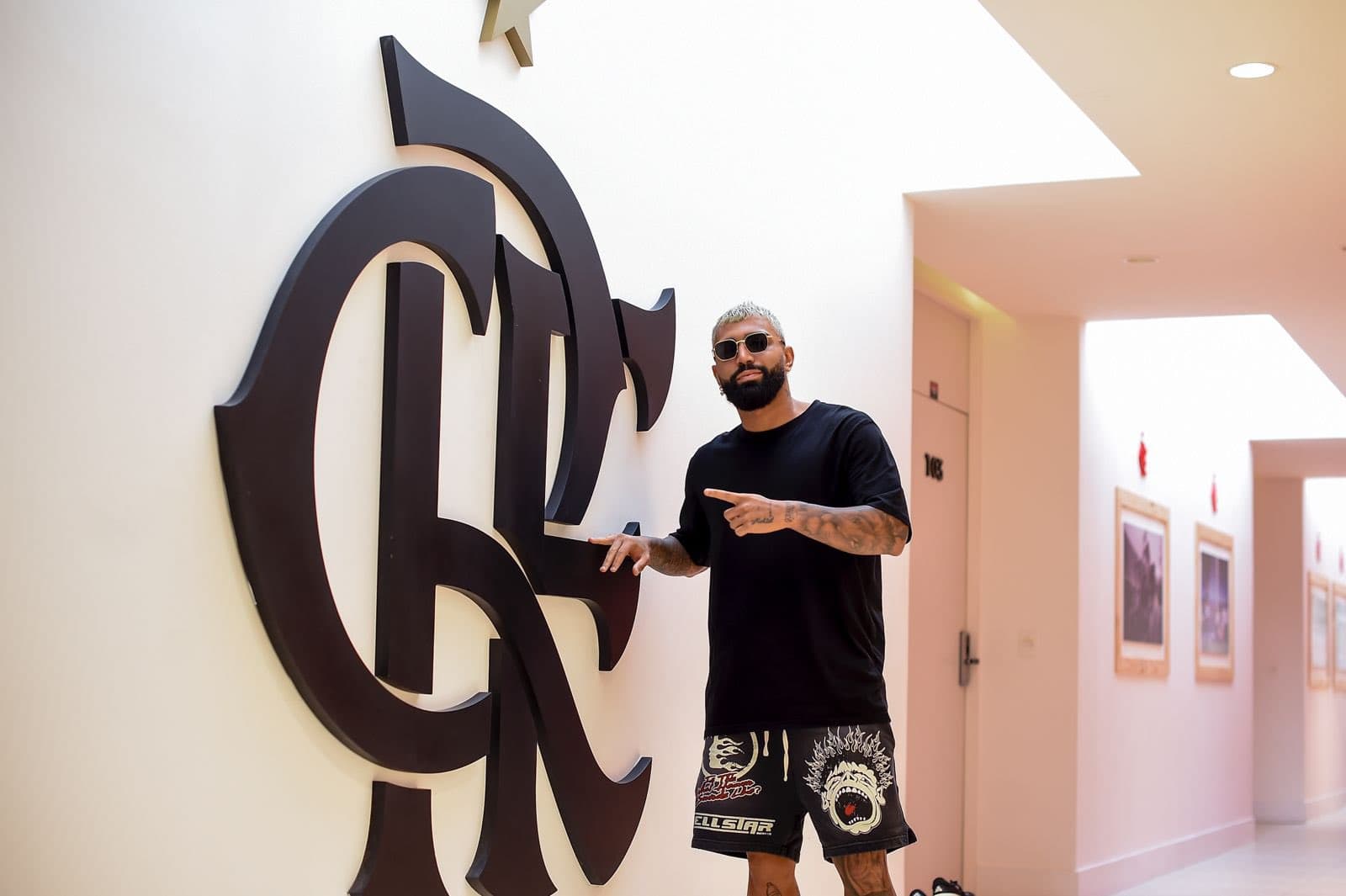 Gabigol posa ao lado de escudo do Flamengo no Ninho do Urubu