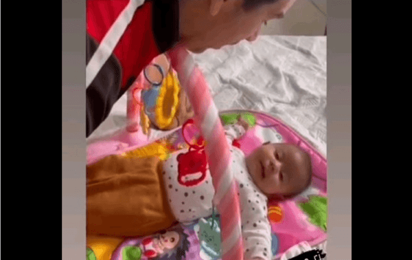 Bebê em uma cama com o pai olhando para a criança.