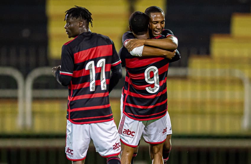 Lorran e Wallace Yan se abraçam durante comemoração do Flamengo Sub-20; Shola olha para trás próximo aos companheiros