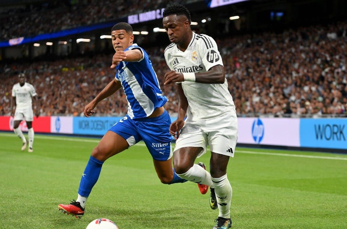 MADRI, ESPANHA - 24 DE SETEMBRO: Vinicius Junior, do Real Madrid, corre com a bola sob pressão de Santiago Mourino, do Alavés, durante a partida da LaLiga entre o Real Madrid CF e o Deportivo Alavés no Estádio Santiago Bernabeu em 24 de setembro de 2024 e