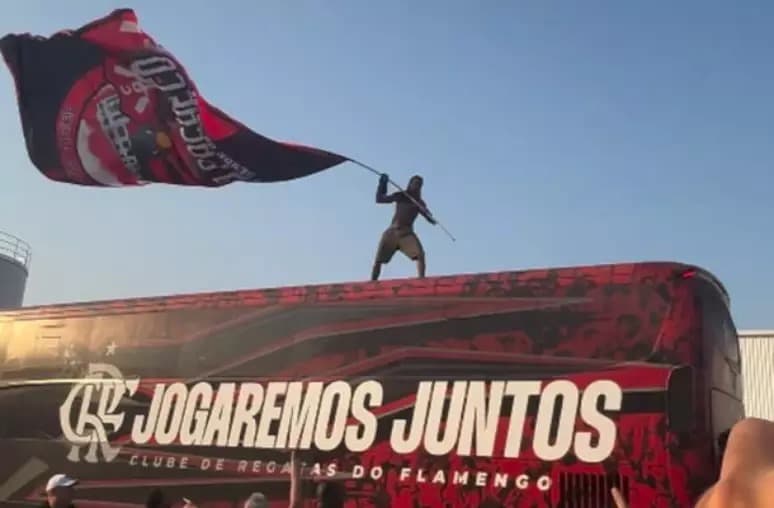 Torcedor do Flamengo, em cima do ónibus do clube, com bandeira.