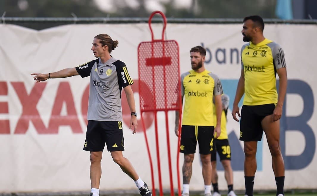 Filipe Luís dando instruções no treino do Flamengo, acompanhado dos zagueiros Léo Pereira e Fabrício Bruno.
