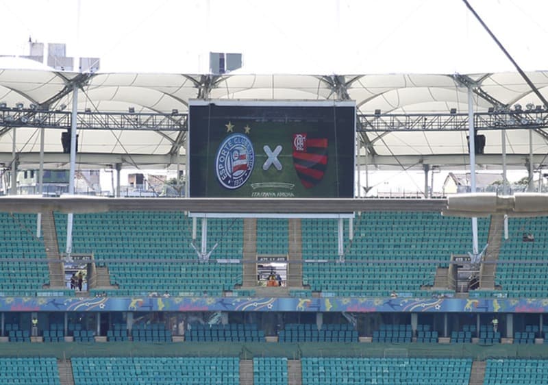 Imagem panorâmica da Fonte Nova antes de Bahia x Flamengo pelo Brasileirão 2023; arquibancada vazia e telão com escudo das duas equipes