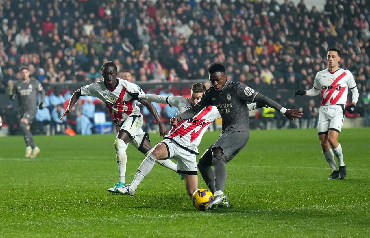 MADRI, ESPANHA - 14 DE DEZEMBRO: Vinicius Junior, do Real Madrid, dá um chute sob pressão de Ivan Balliu, do Rayo Vallecano, durante a partida da LaLiga EA Sports entre Rayo Vallecano e Real Madrid no Estádio de Vallecas em 14 de dezembro de 2024 em Madri