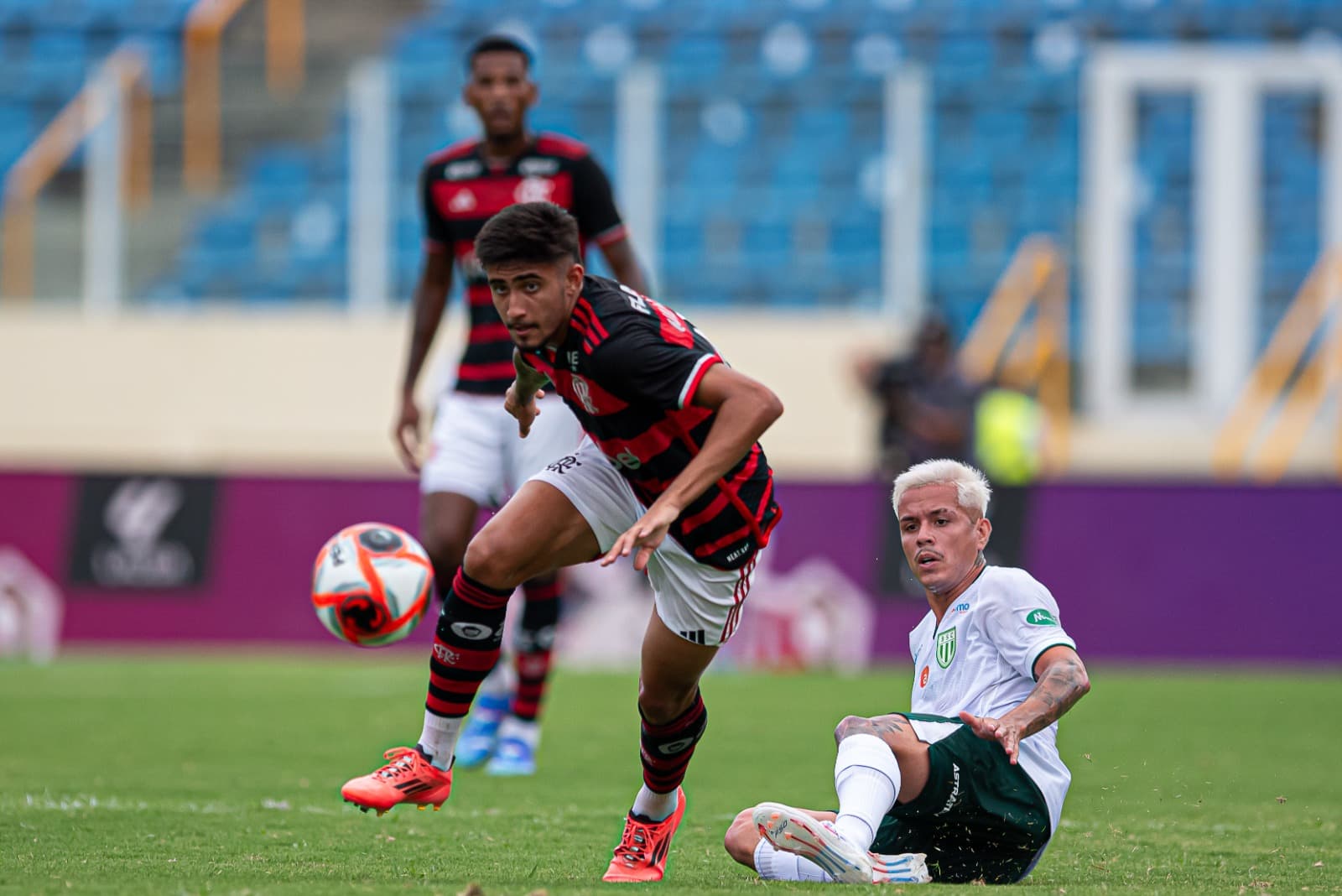 Guilherme dá passe em Flamengo x Boavista enquanto adversário observa sentado no chão