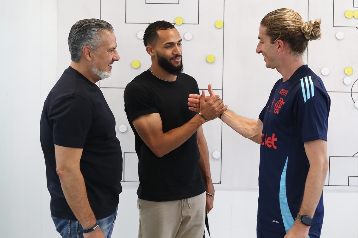 Filipe Luís cumprimenta Juninho enquanto José Boto só observa