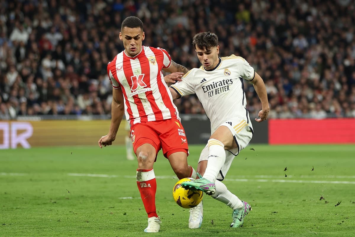 Vestindo a camisa vermelha e branca do Almería, Kaiky disputa bola com Brahim Díaz em jogo contra o Real Madrid