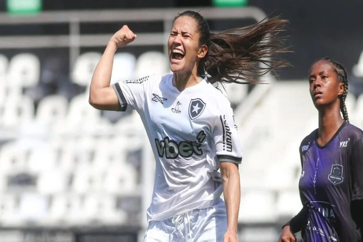 Jogadora do Botafogo comemora com o braço levantado no Engenhão e logo atrás está uma jogadora do Pérolas com a expressão séria