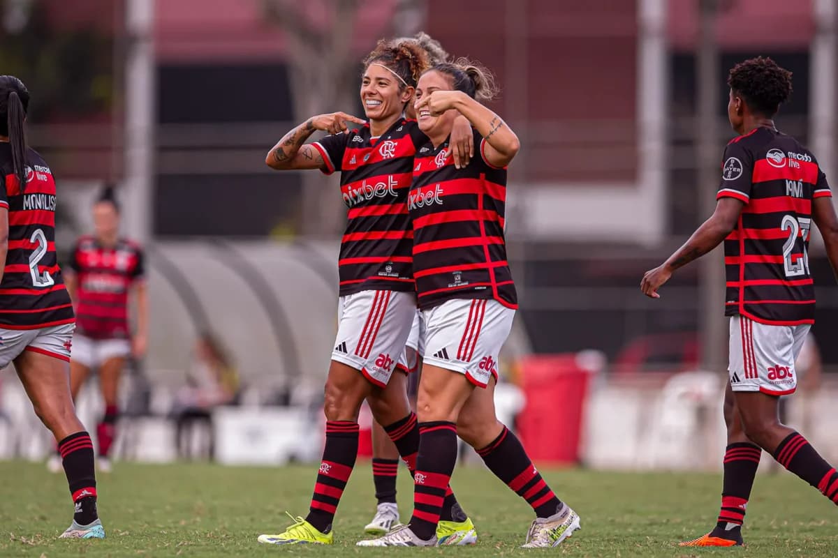 Glaucia e Cris caminham para o centro do campo após gol, uma está apontando para a outra