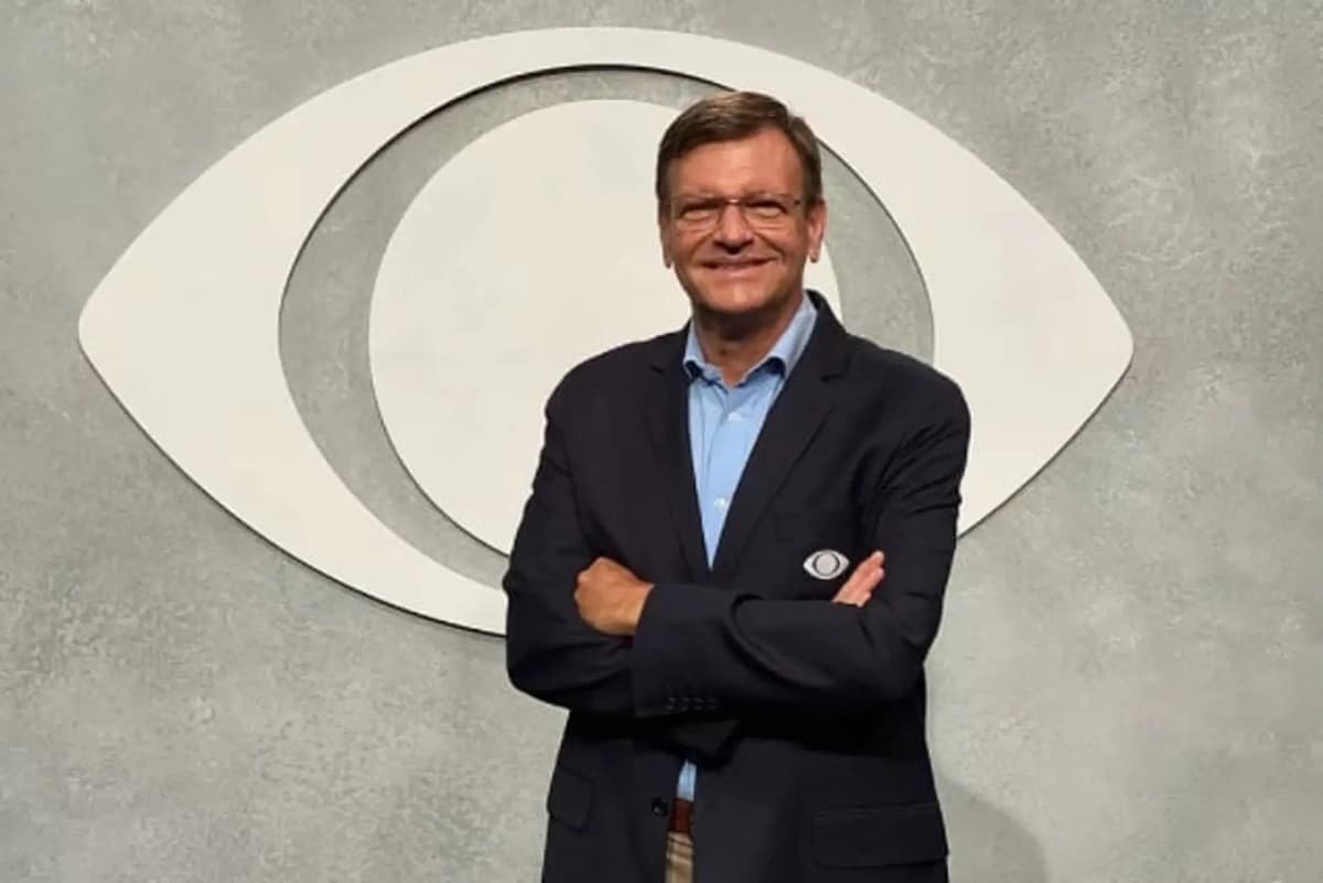 Em foto de apresentação, Sérgio Mauricio sorri com o logotipo da Band ao fundo