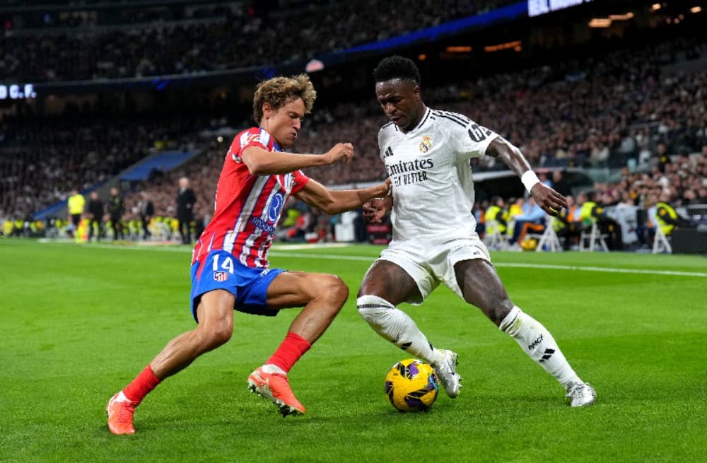 MADRI, ESPANHA – 08 DE FEVEREIRO: Vinicius Junior, do Real Madrid, é desafiado por Marcos Llorente, do Atlético de Madrid, durante a partida da LaLiga entre Real Madrid CF e Atlético de Madrid no Estádio Santiago Bernabéu, em 08 de fevereiro de 2025, em M