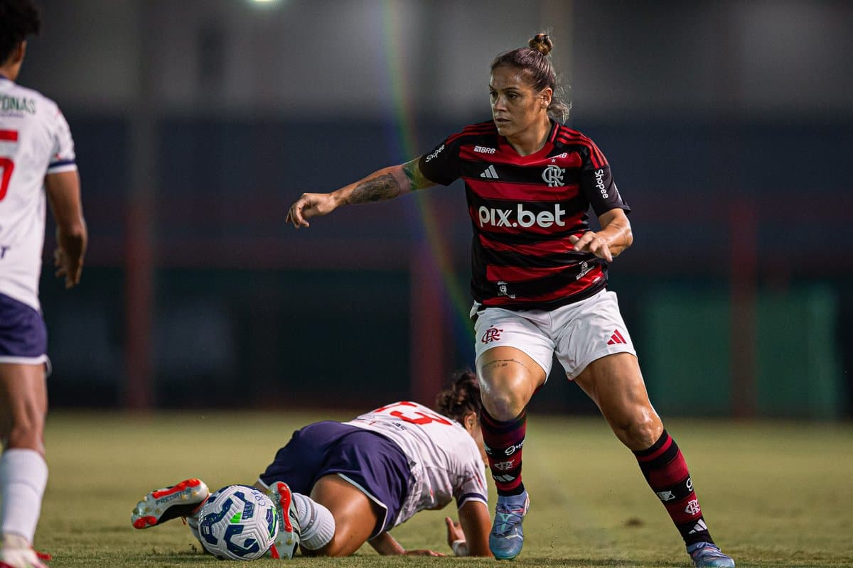 Glaucia conduz a bola enquanto uma jogadora do 3B está no chão e outra chegar para marcar