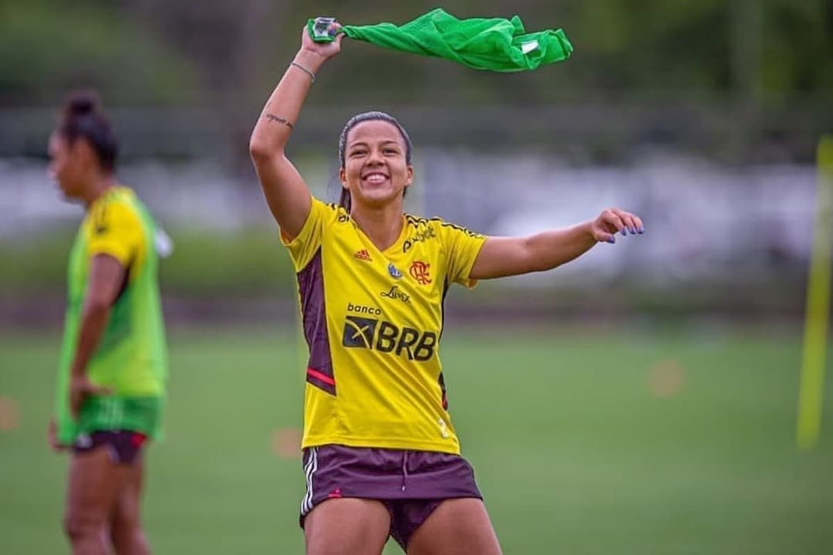 Monalisa está sorrindo e girando o colete de treino acima da cabeça