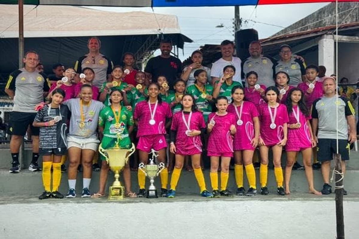 Comissão técnica do Flamengo posa para foto com as campeãs do torneio, a comissão está com o unifrome do clube e as atletas estão de uniforme rosa com as medalhas penduradas no peito