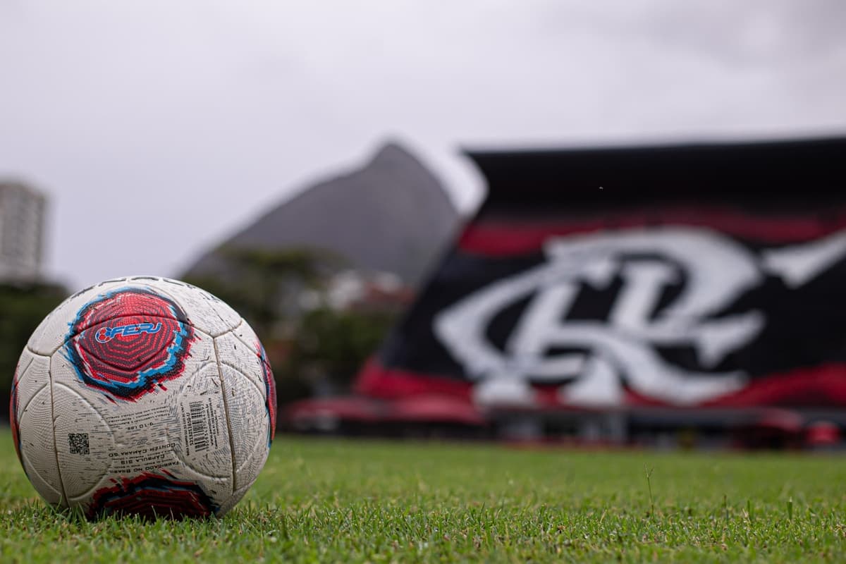 A bola que será utilizada no jogo está em destaque, a logo da FERJ está aparente e ao fundo é possível ver a arquibancada da Gávea recentemente revitalizada