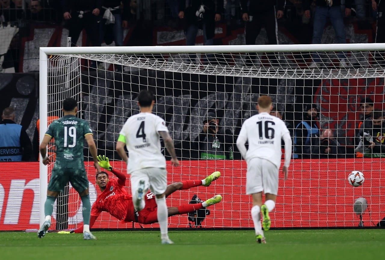 Kaua Santos, do Eintracht Frankfurt, não consegue defender um pênalti de Dominic Solanke, do Tottenham Hotspur, que marca o primeiro gol de sua equipe, após cometer falta em James Maddison, do Tottenham Hotspur (não mostrado na foto)
