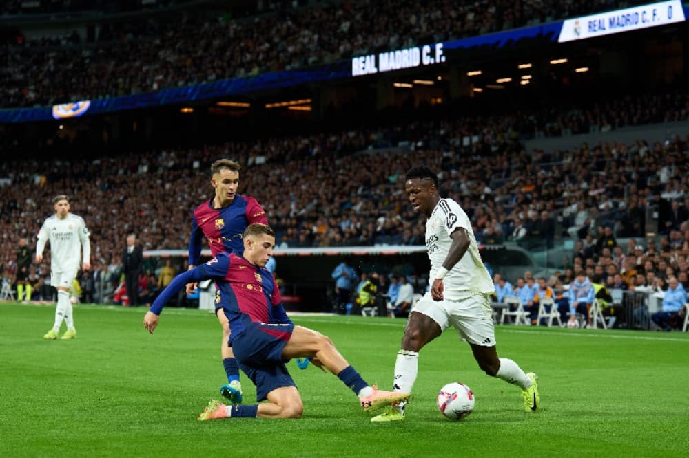 Vinicius Junior, do Real Madrid, é desafiado por Fermin Lopez, do FC Barcelona, ​​durante a partida da LaLiga entre Real Madrid CF e FC Barcelona no Estádio Santiago Bernabeu em 26 de outubro de 2024 em Madri, Espanha.