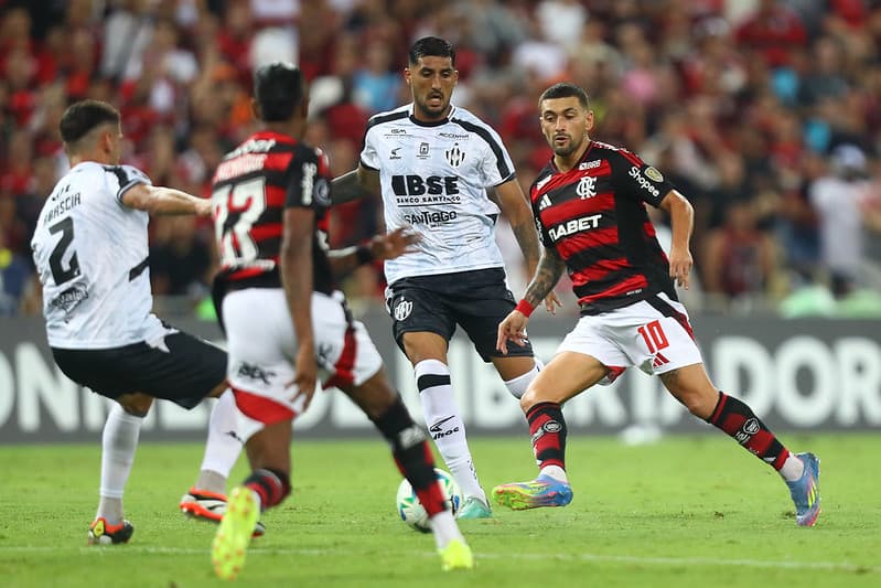 Arrascaeta e Bruno Henrique disputam bola no Maracanã com jogadores adversários em Flamengo x Central Córdoba