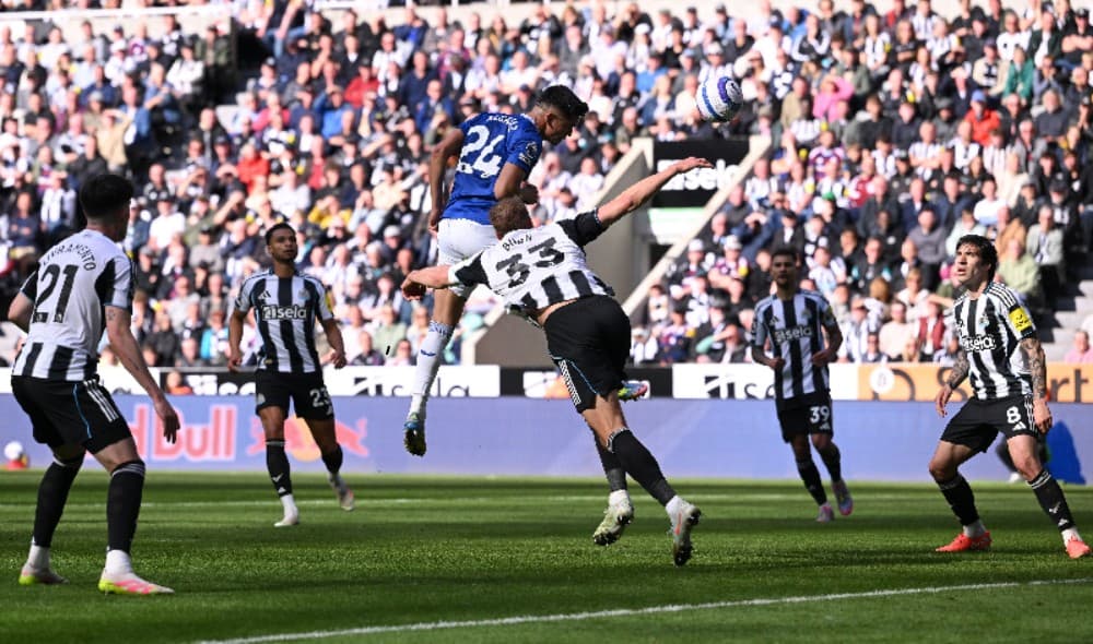 O jogador do Newcastle Dan Burn (#33) observa enquanto Carlos Alcaraz, do Everton, sobe de cabeça para marcar o gol da vitória durante a partida da Premier League entre Newcastle United FC e Everton FC no St James' Park em 25 de maio de 2025 em Newcastle