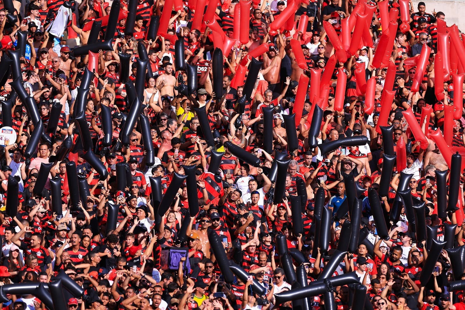 Torcedores do Flamengo seguram balões vermelhos e pretos no momento da entrada do time em campo