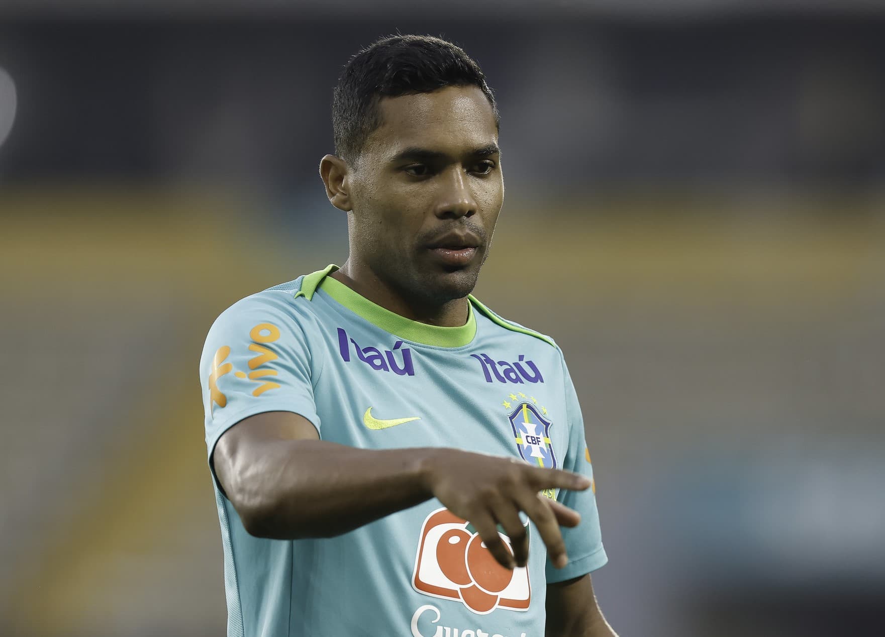 Alex Sandro com o uniforme da Seleção Brasileira aponta para frente em treinamento