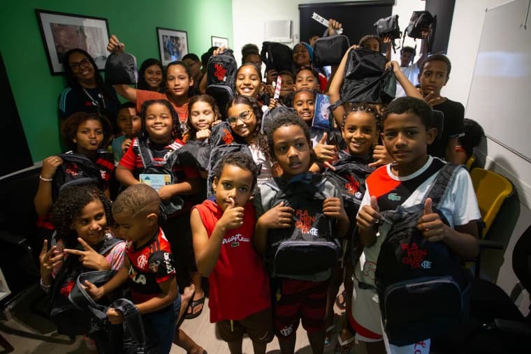 Crianças com livros e mochilas do Flamengo durante evento no Complexo do Alemão