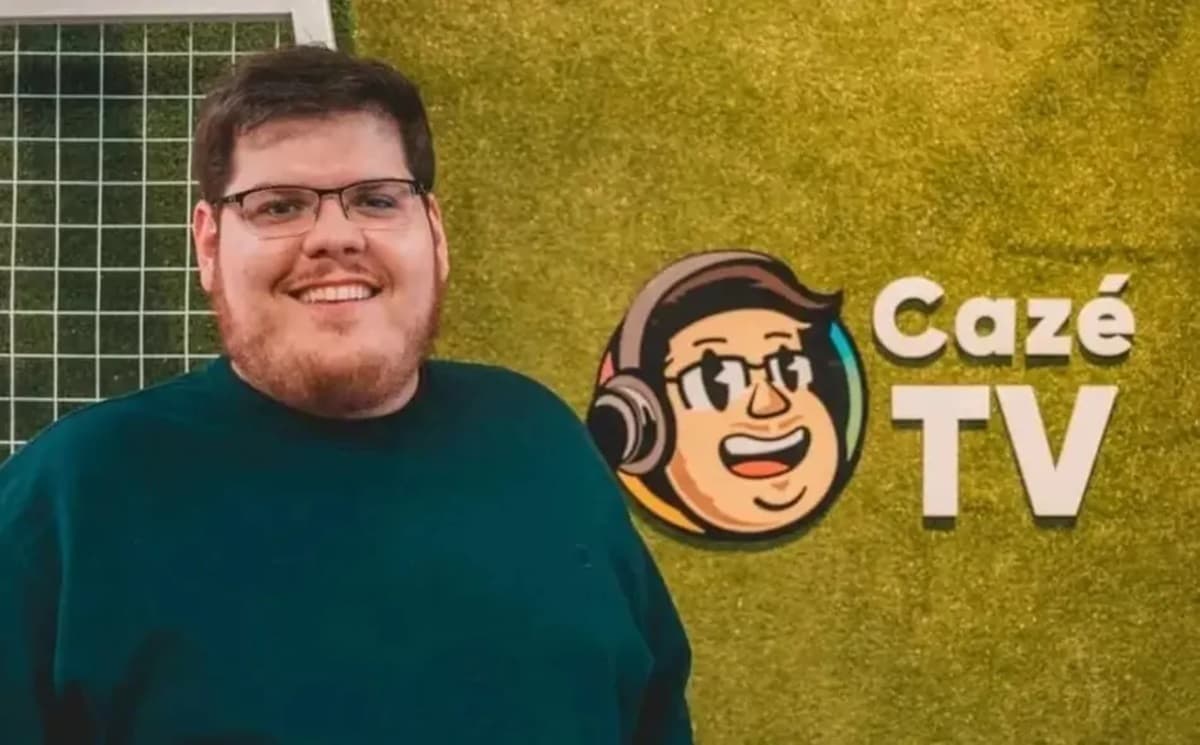 Casimiro posa ao lado da marca da Cazé TV