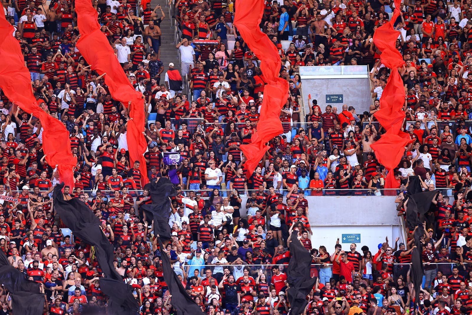 Torcedores do Flamengo no Maracanã; faixas rubro-negras verticais passam pela torcida de cima a baixo