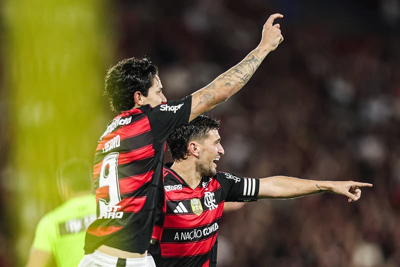 Pedro e Arrascaeta se abraçam e apontam para frente em comemoração de gol da goleada por 8 a 0 sobre o Vitória, no Maracanã, pelo Brasileirão