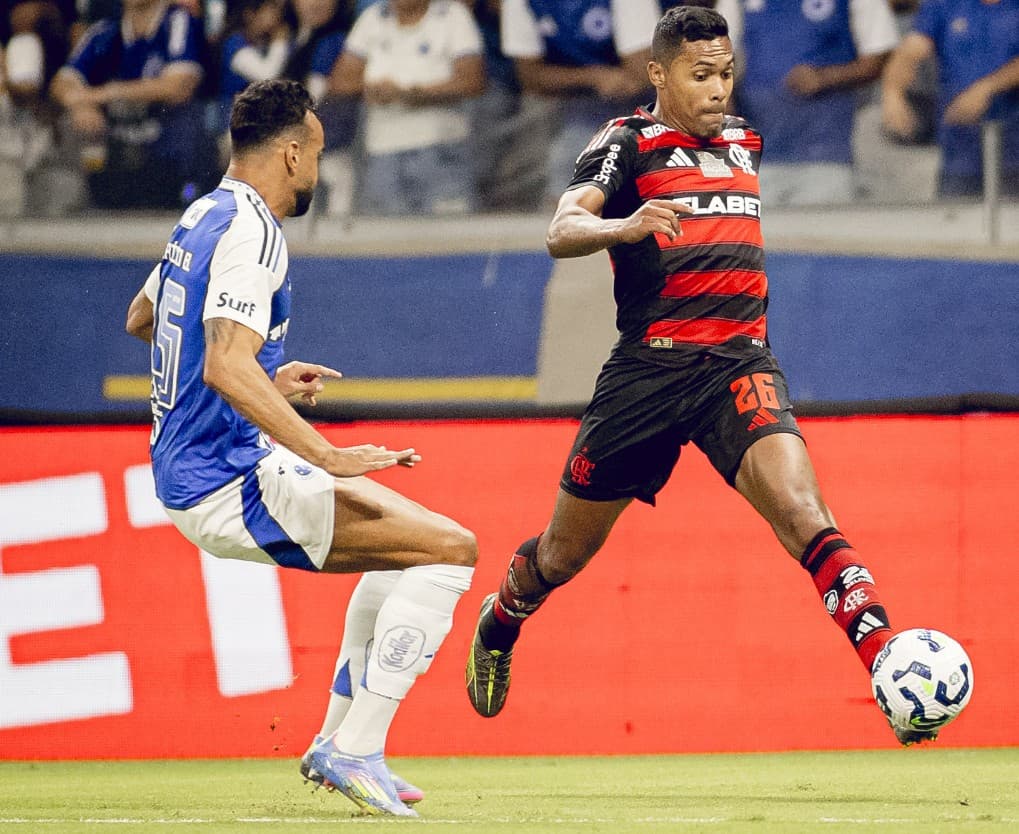 Alex Sandro, do Flamengo, conduz a bola em duelo contra marcador do Cruzeiro durante partida do Brasileirão 2025