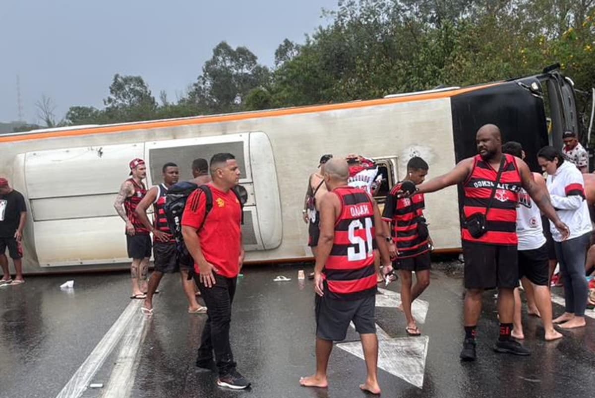 Torcedores do Flamengo andam pela pista em frente a ônibus tombado em Barra Mansa