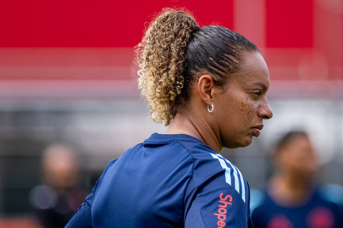 Rosana Augusto com semblante sério e de perfil observando compenetrada