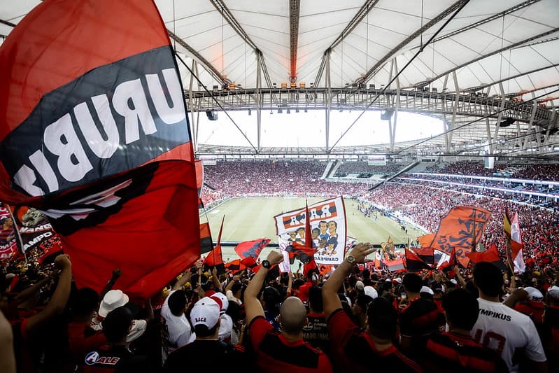 Torcida do Flamengo no Maracanã enquanto assiste ao jogo contra o Palmeiras; camera posicionada na Norte, atrás dos torcedores