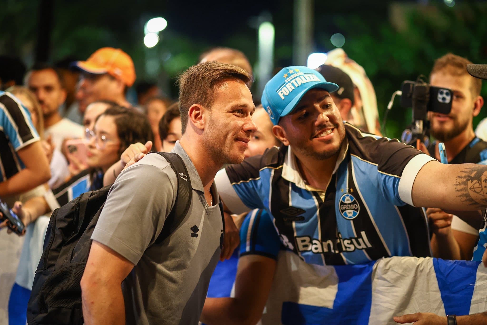 Arthur Melo atende e tira foto com torcedor do Grêmio na chegada do elenco ao Ceará