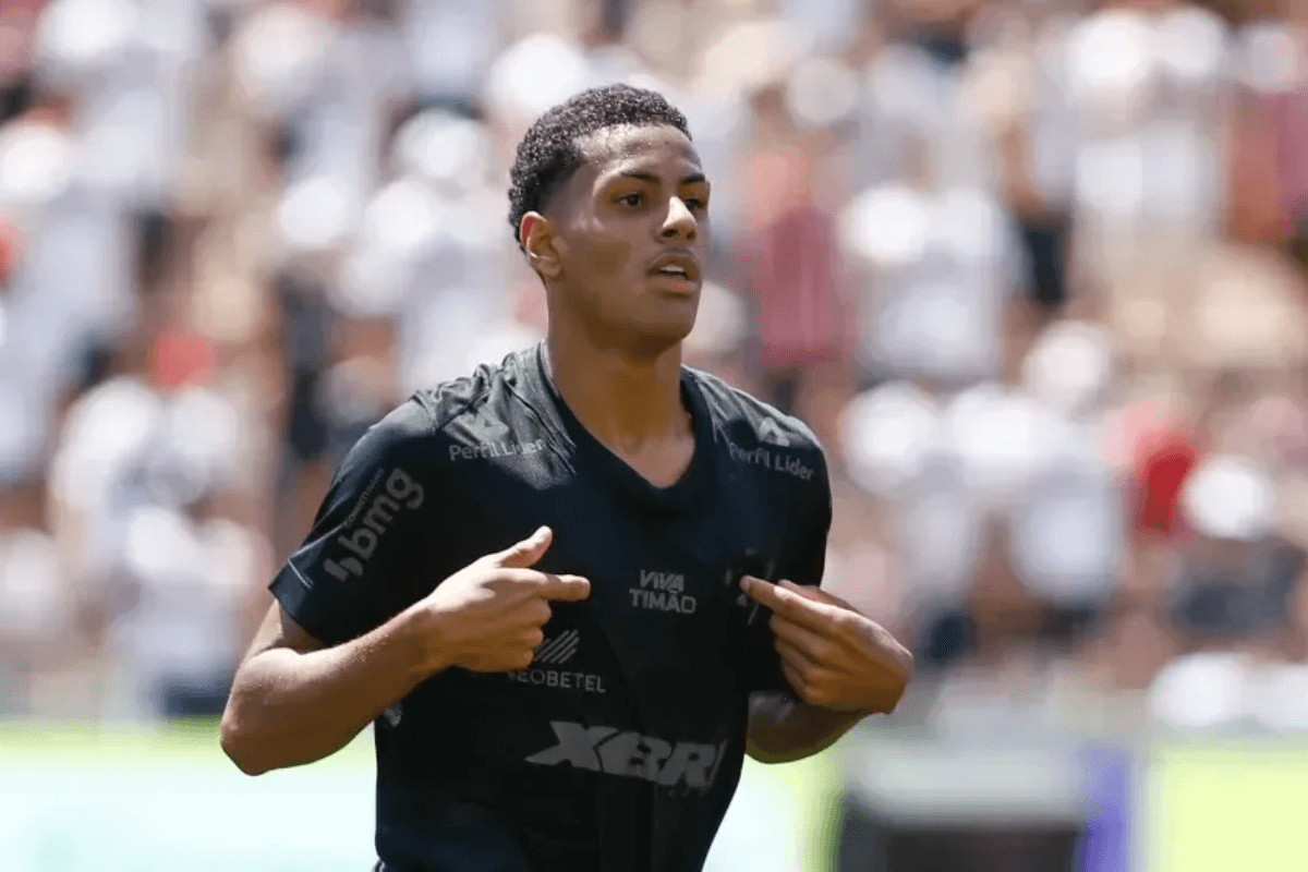 Denner, jogador das divisões de base do Corinthians, comemora gol apontando para o escudo do time no uniforme
