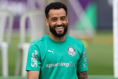 Felipe Anderson, jogador do Palmeiras, usando a camisa de treino do clube alviverde, sorri para a foto