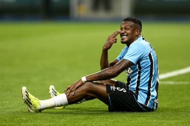 Sentado no gramado, Edenílson faz sinal com o dedo nos olhos durante jogo entre Grêmio e São Paulo