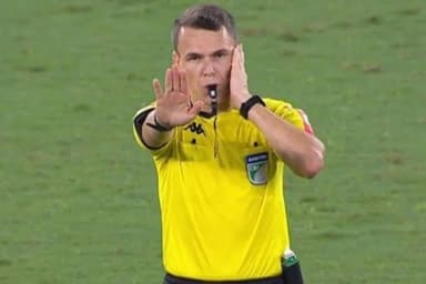 Árbitro Paulo Cesar Zanovelli com uma mão no ouvido, a outra em riste aberta e com o apito na boca durante jogo do Brasileirão