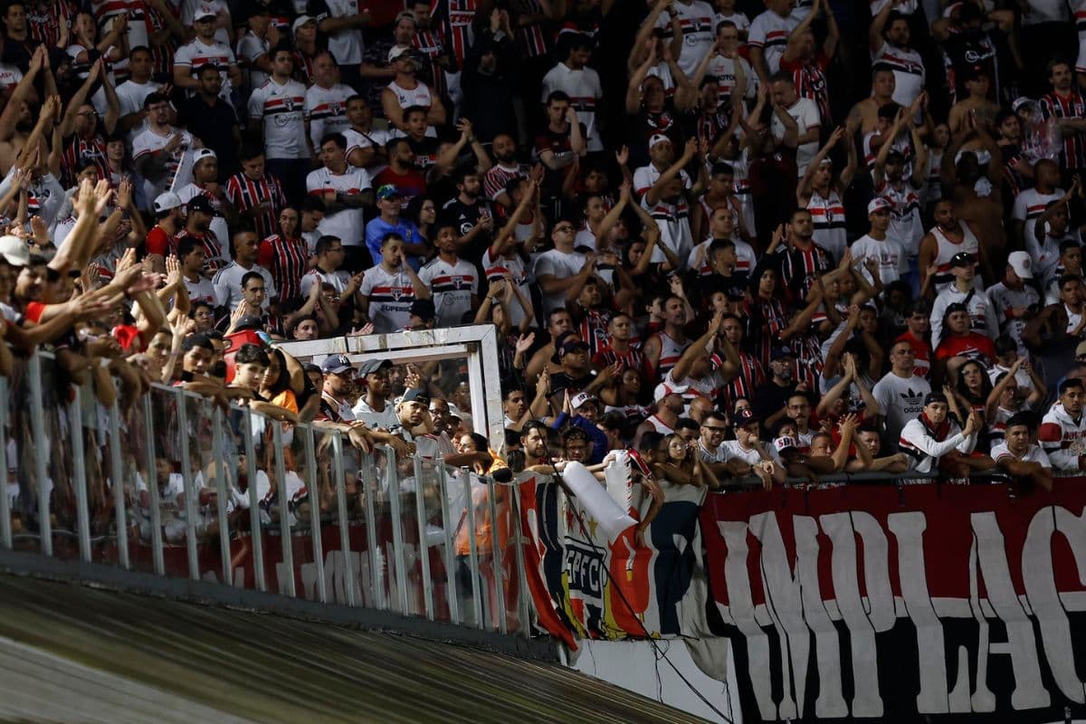Torcedores do São Paulo aplaudindo e fazendo gestos com as mãos nas arquibancadas da Vila Belmiro durante jogo contra o Flamengo no Campeonato Brasileiro 2025
