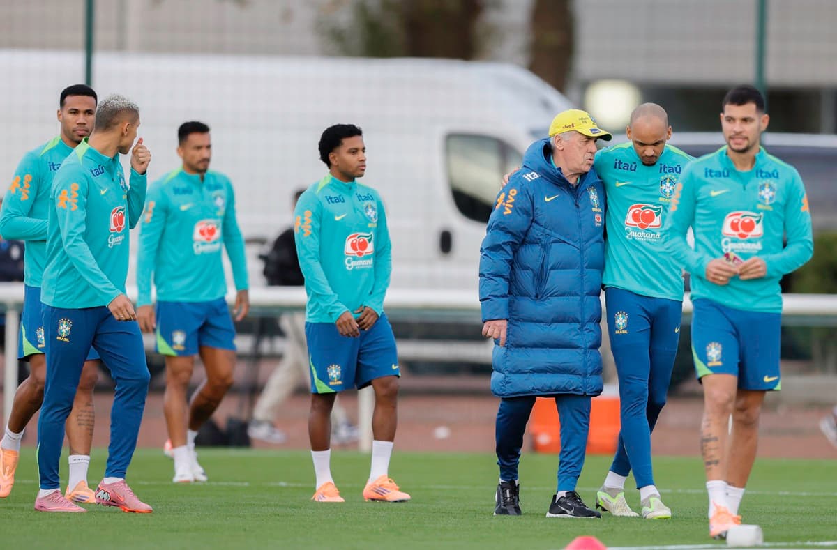 Ancelotti conversa com jogadores enquanto anda para o campo em treino em Londres