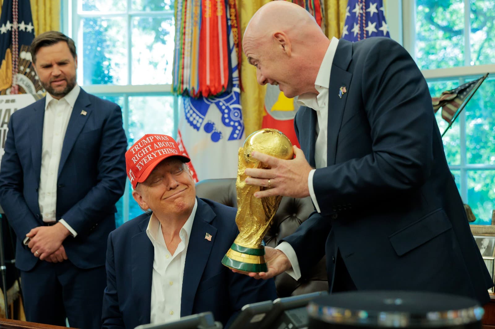 O presidente da FIFA, Gianni Infantino, mostra o troféu da Copa do Mundo ao presidente dos EUA, Donald Trump, no Salão Oval, enquanto o vice-presidente JD Vance observa, em 22 de agosto de 2025, em Washington, D.C. Trump anunciou que o sorteio da Copa do