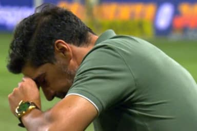 Abel Ferreira, treinador do Palmeiras, agachado e com a mão no rosto