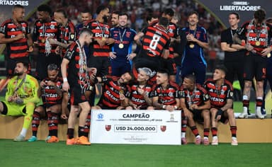 Jogadores do Flamengo, separados em diferentes grupos, tiram fotos com a medalha no palco da Libertadores