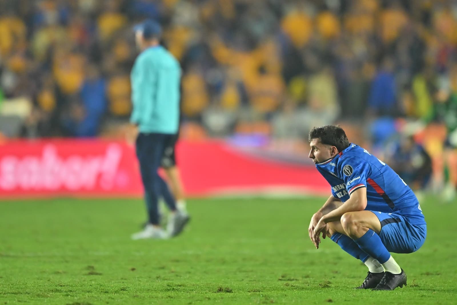 jogador do cruz azul, agachado, lamenta mordendo a camiseta, a eliminação do time na liga mexicana, para o tigres