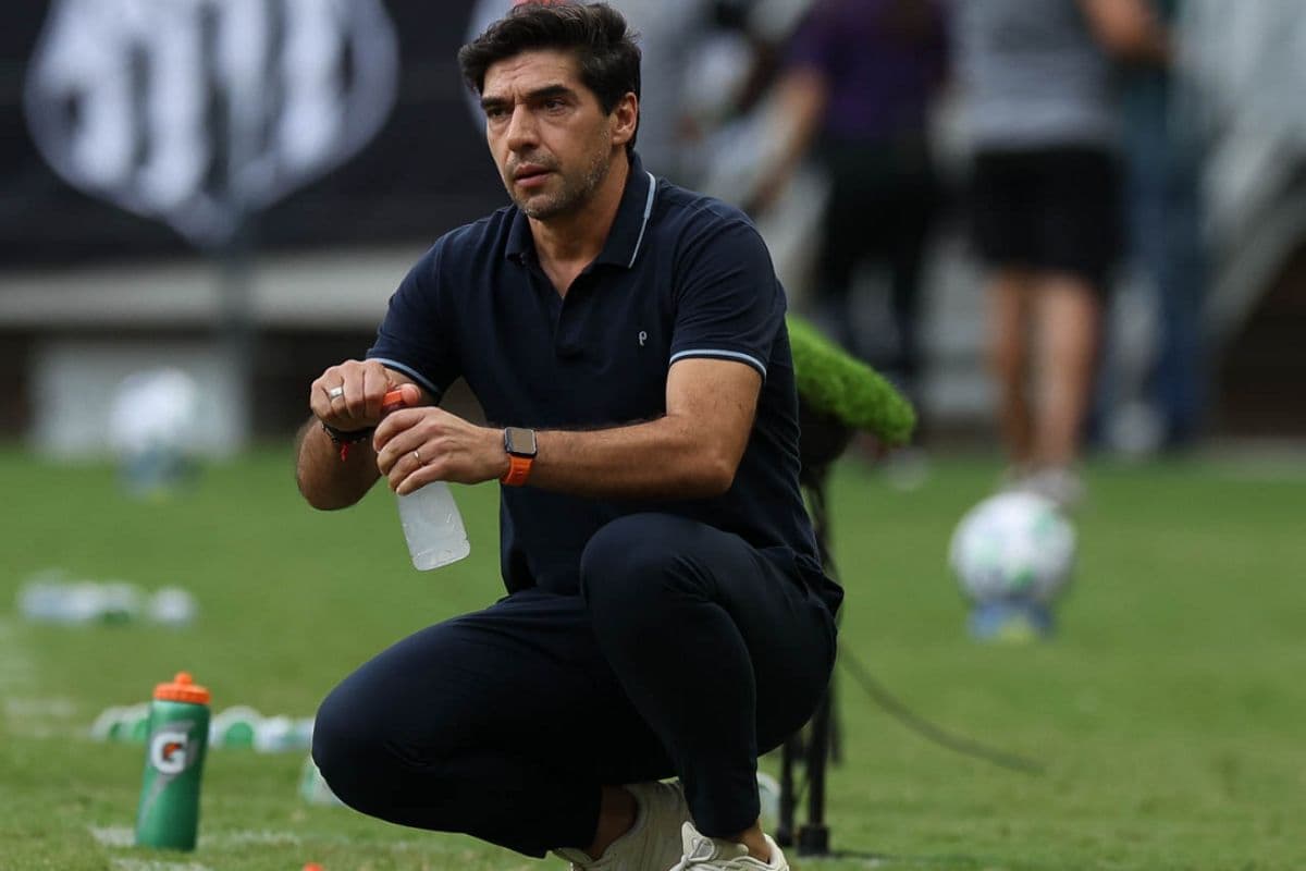 Abel Ferreira, treinador do Palmeiras, agachado e segurando uma garrafa d'água