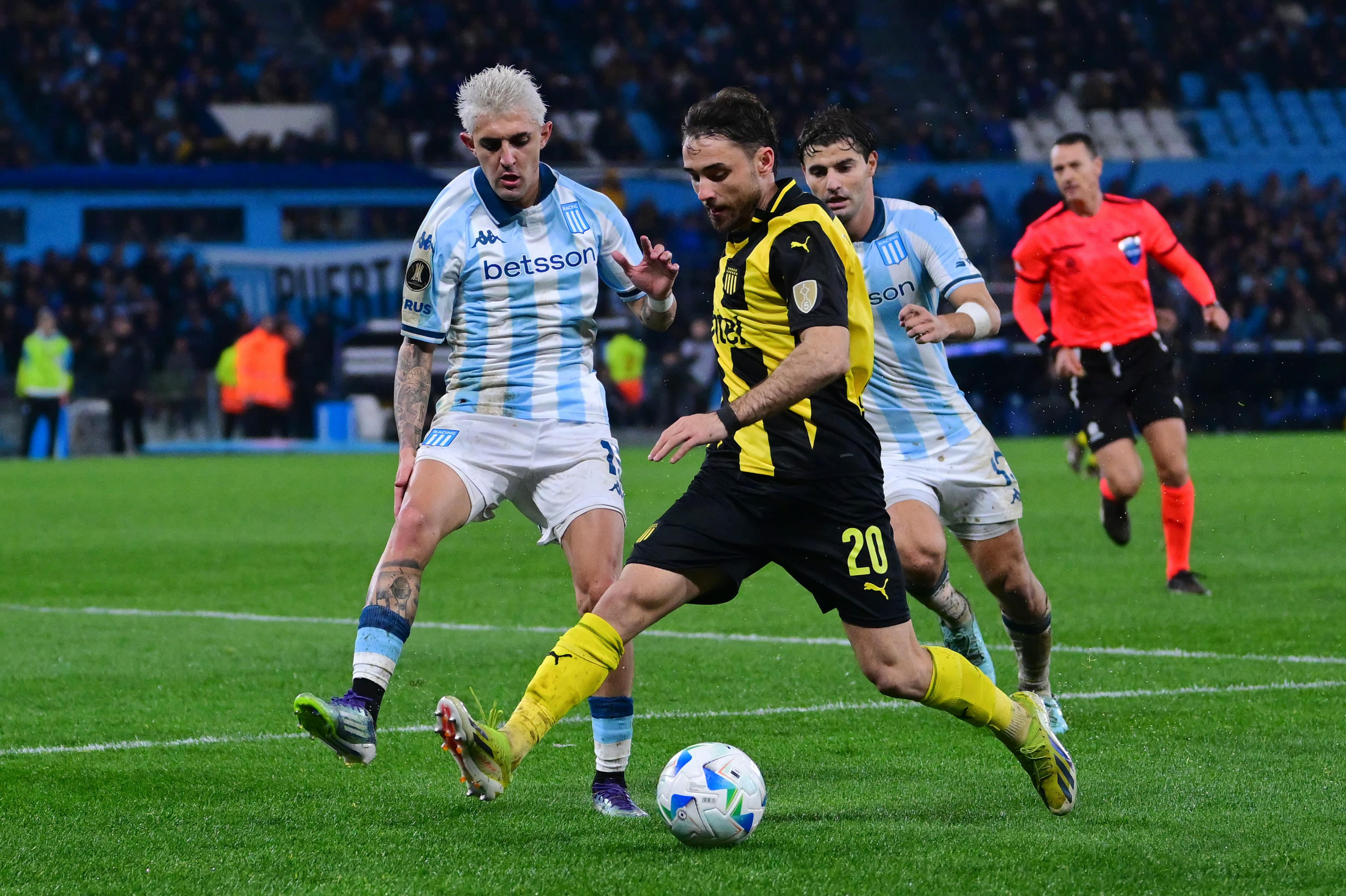 Pedro Milans, do Peñarol, prepara um passe enquanto é cercado por jogadores do Racing, durante um jogo da Libertadores 2025