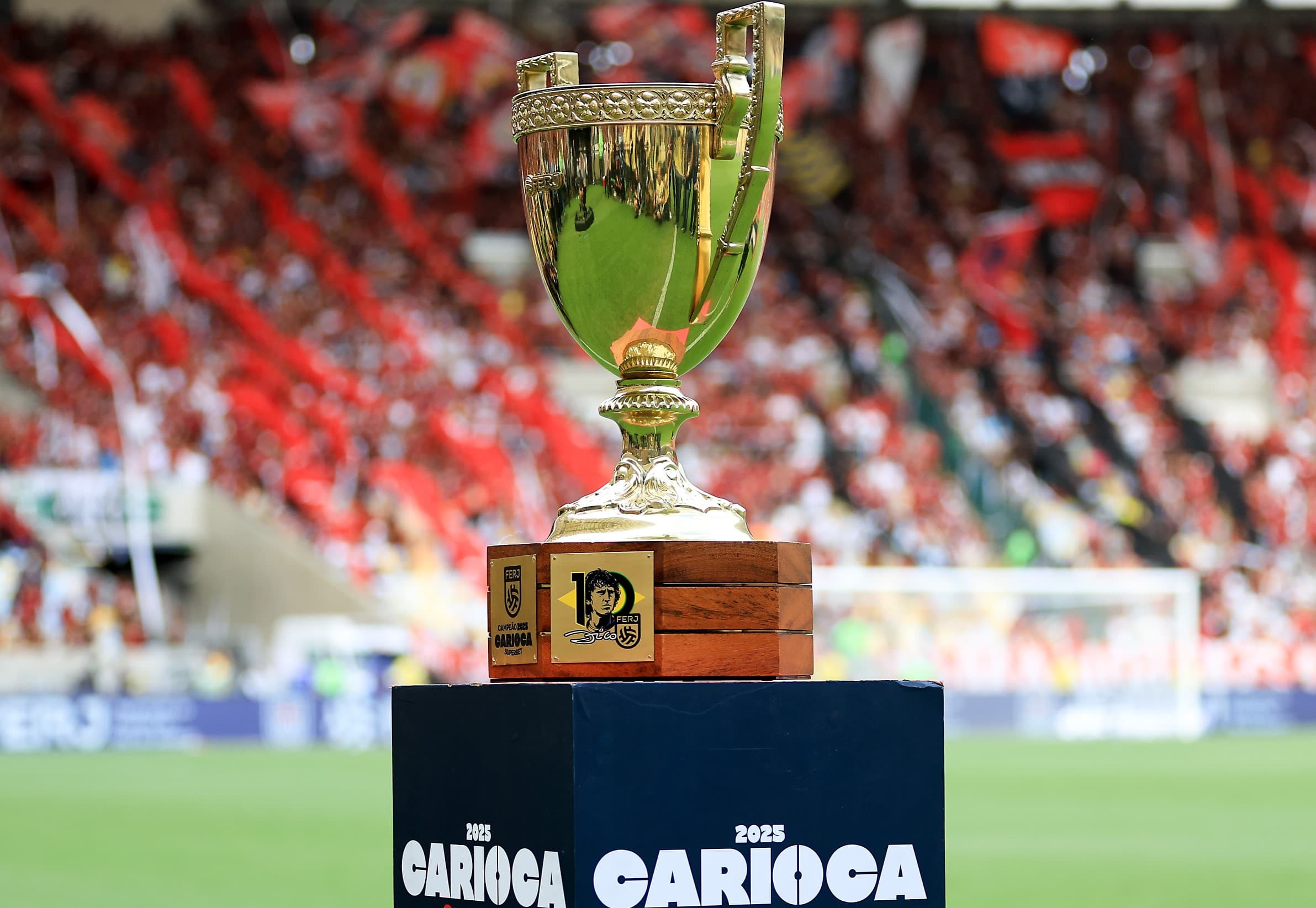 Troféu Campeonato Carioca 2025; ao fundo, torcida do Flamengo
